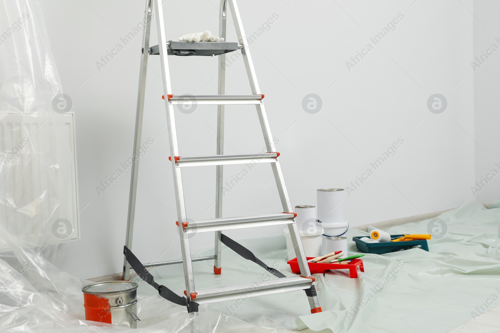 Photo of Metallic folding ladder and painting tools indoors