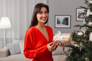 Photo of Smiling woman opening Christmas gift at home