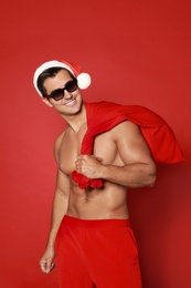Sexy shirtless Santa Claus on red background