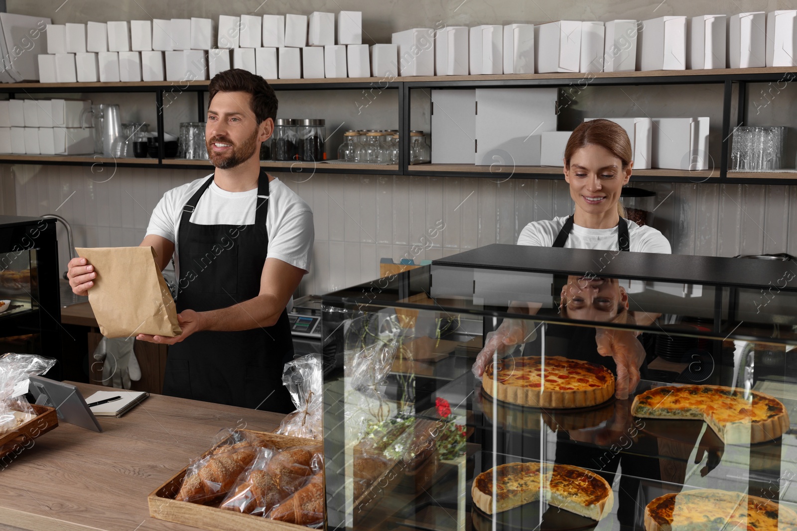 Photo of Two happy sellers working in bakery shop