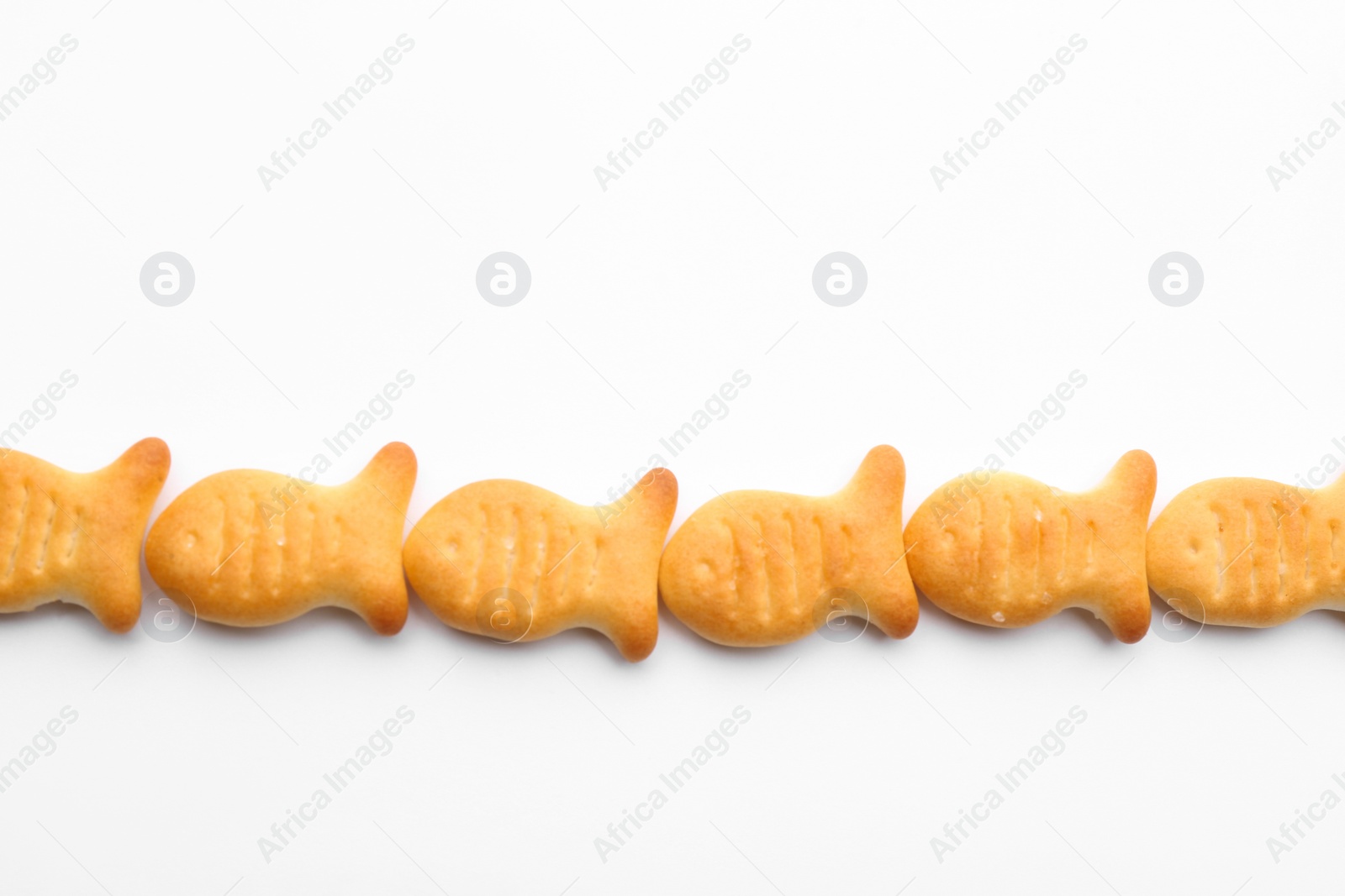 Photo of Delicious crispy goldfish crackers on white background, top view