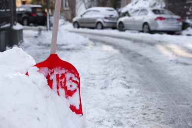 Shovel in snowdrift on city street. Space for text