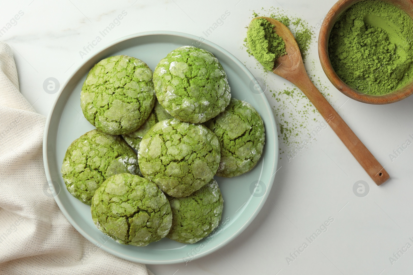 Photo of Plate with tasty matcha cookies and powder on white table, flat lay