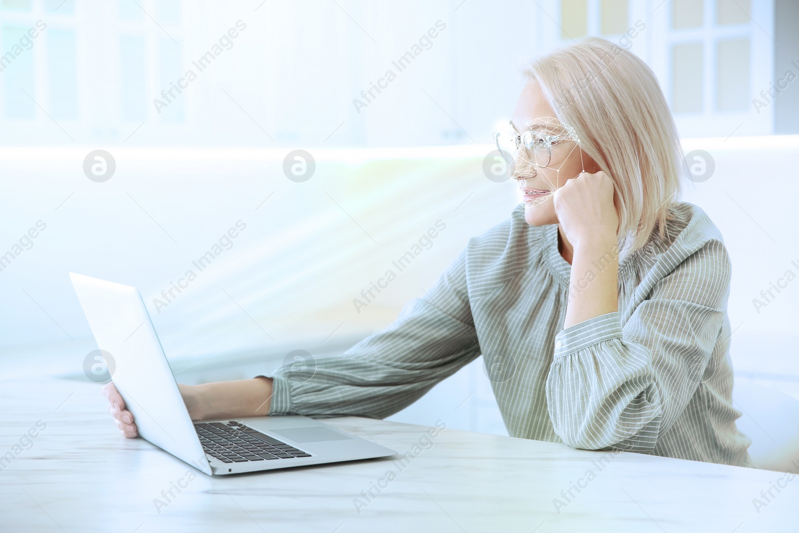 Image of Facial recognition system. Mature woman using laptop in kitchen 