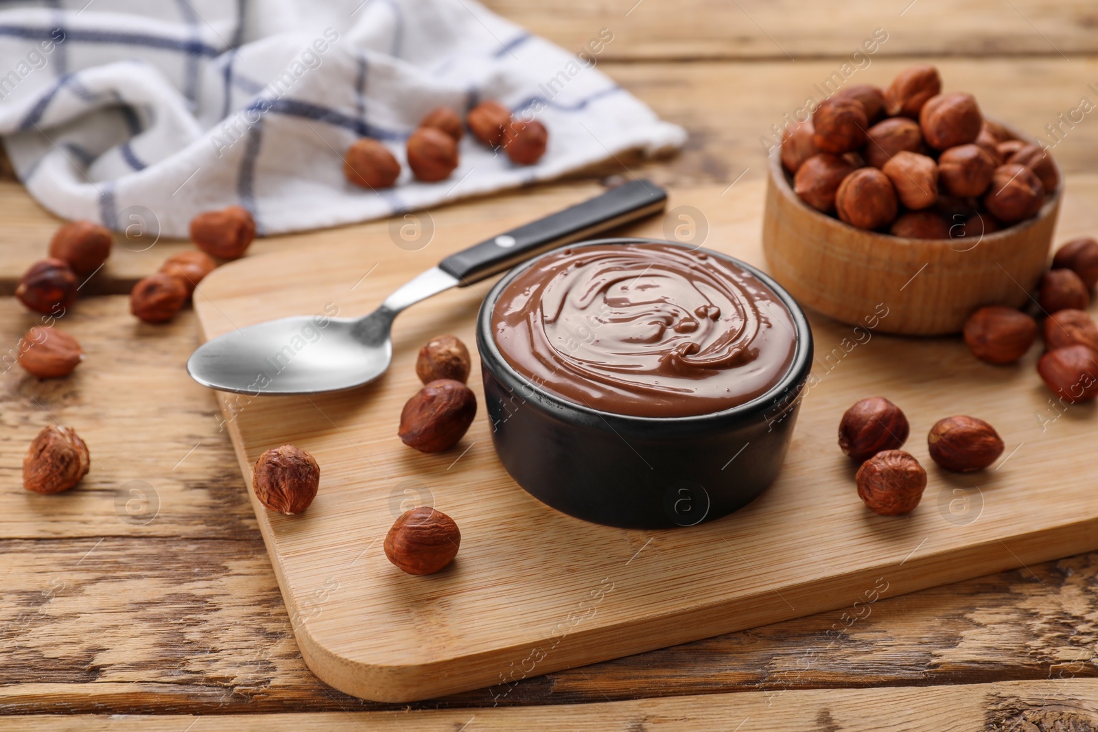 Photo of Bowl with delicious chocolate paste and nuts on wooden table
