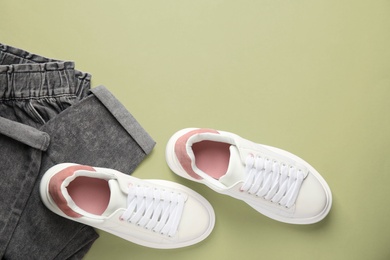 Photo of Stylish white sneakers and jeans on red background, flat lay