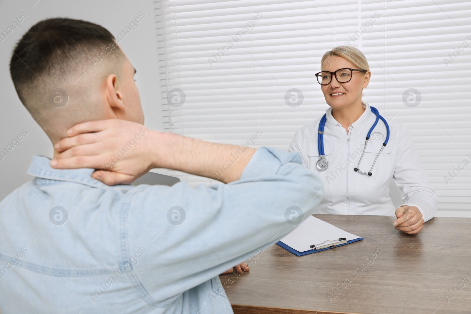 Photo of Professional doctor consulting patient at wooden table in clinic