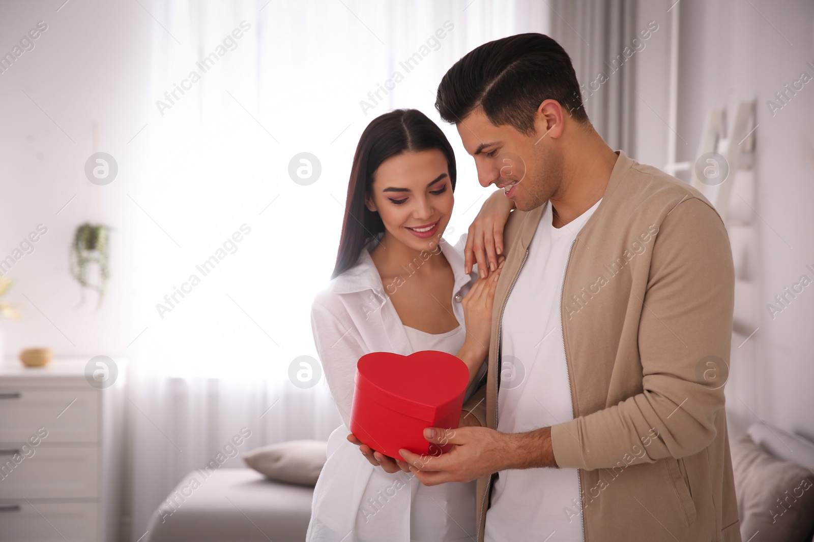 Photo of Lovely couple with gift box at home. Valentine's day celebration