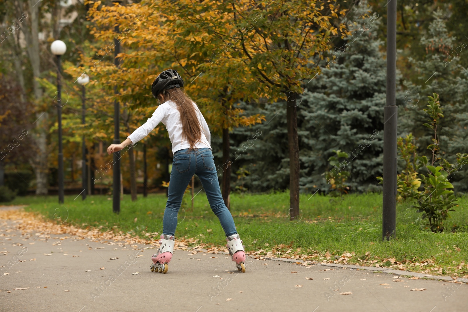 Photo of Cute girl roller skating in autumn park. Space for text