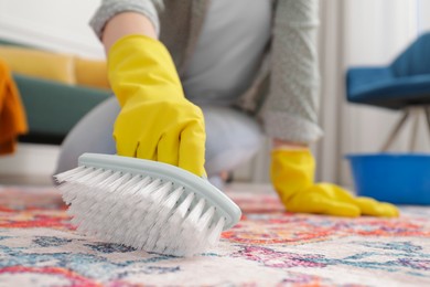 Woman cleaning carpet with brush indoors, closeup. Space for text