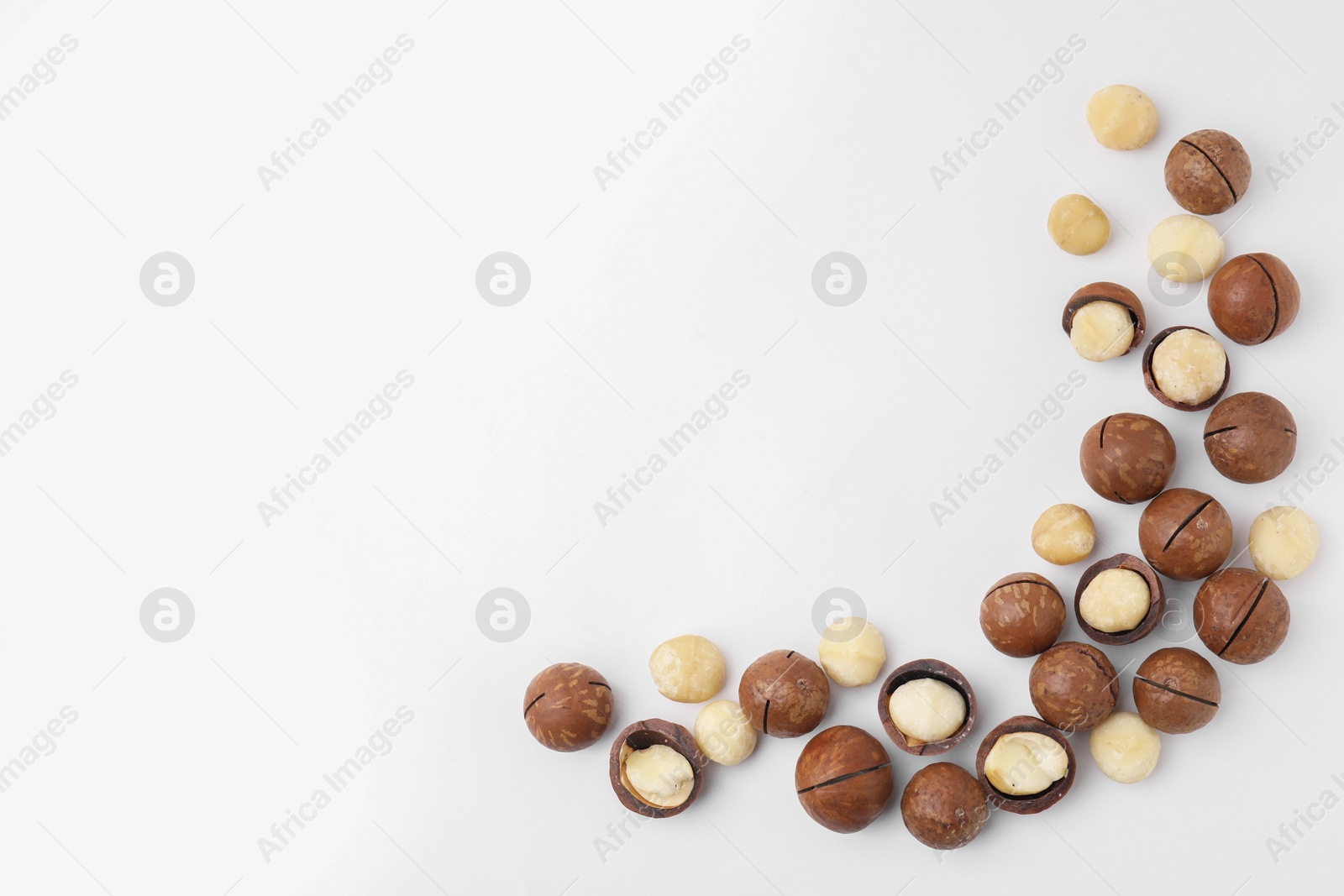 Photo of Tasty Macadamia nuts on white background, flat lay. Space for text