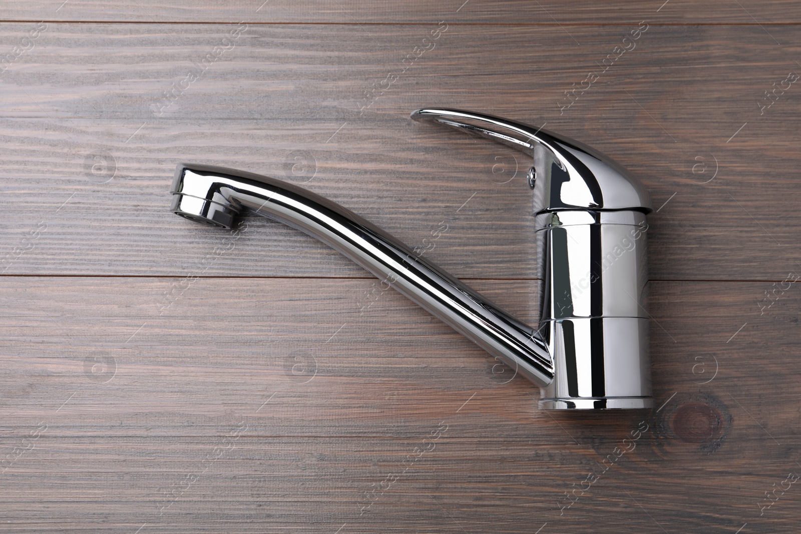 Photo of Single handle water tap on wooden table, top view