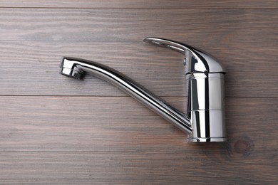 Photo of Single handle water tap on wooden table, top view