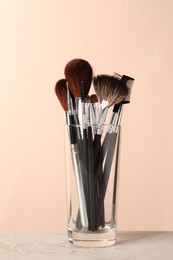 Set of professional makeup brushes on grey table against beige background