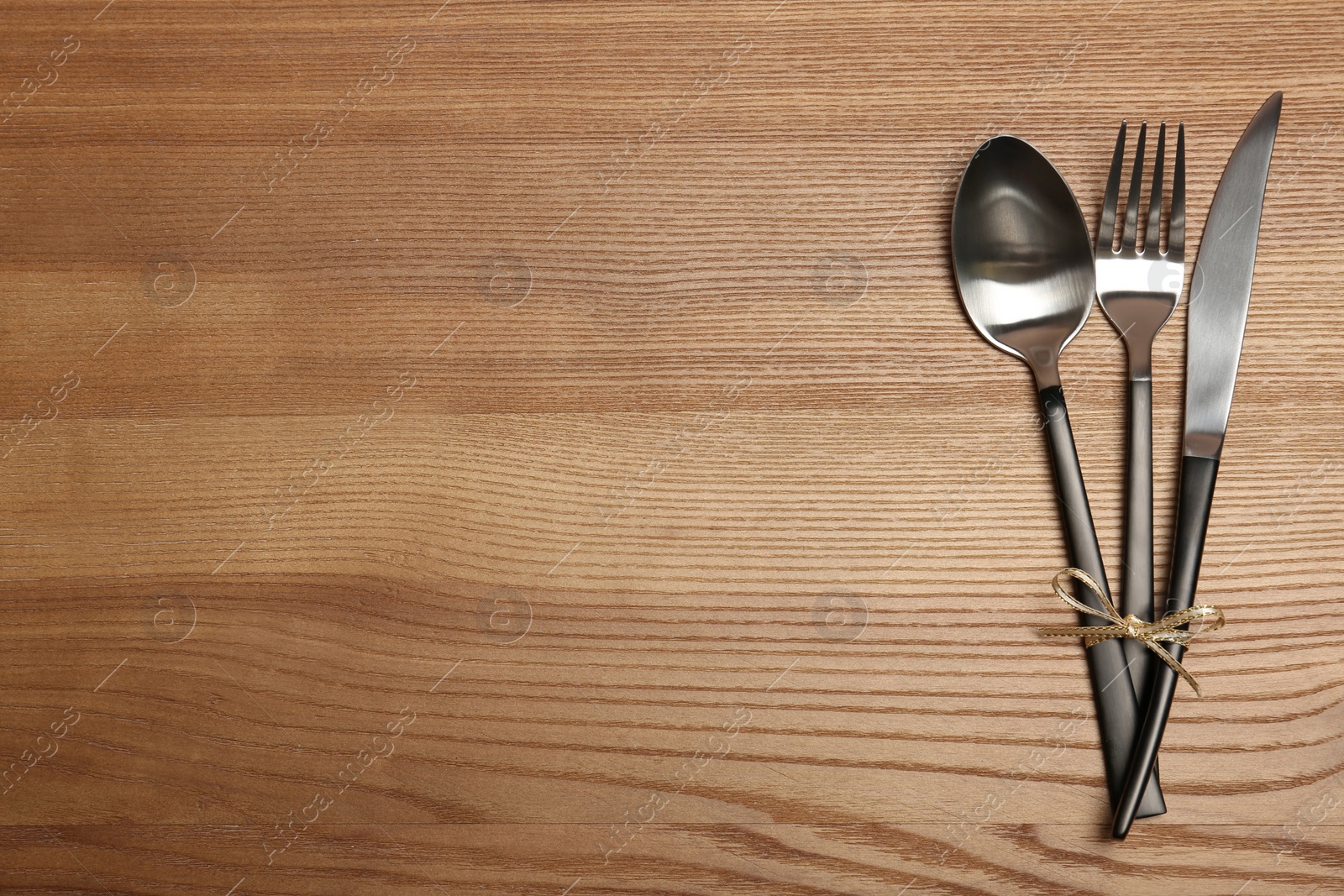 Photo of Silver cutlery on wooden background, top view. Table setting