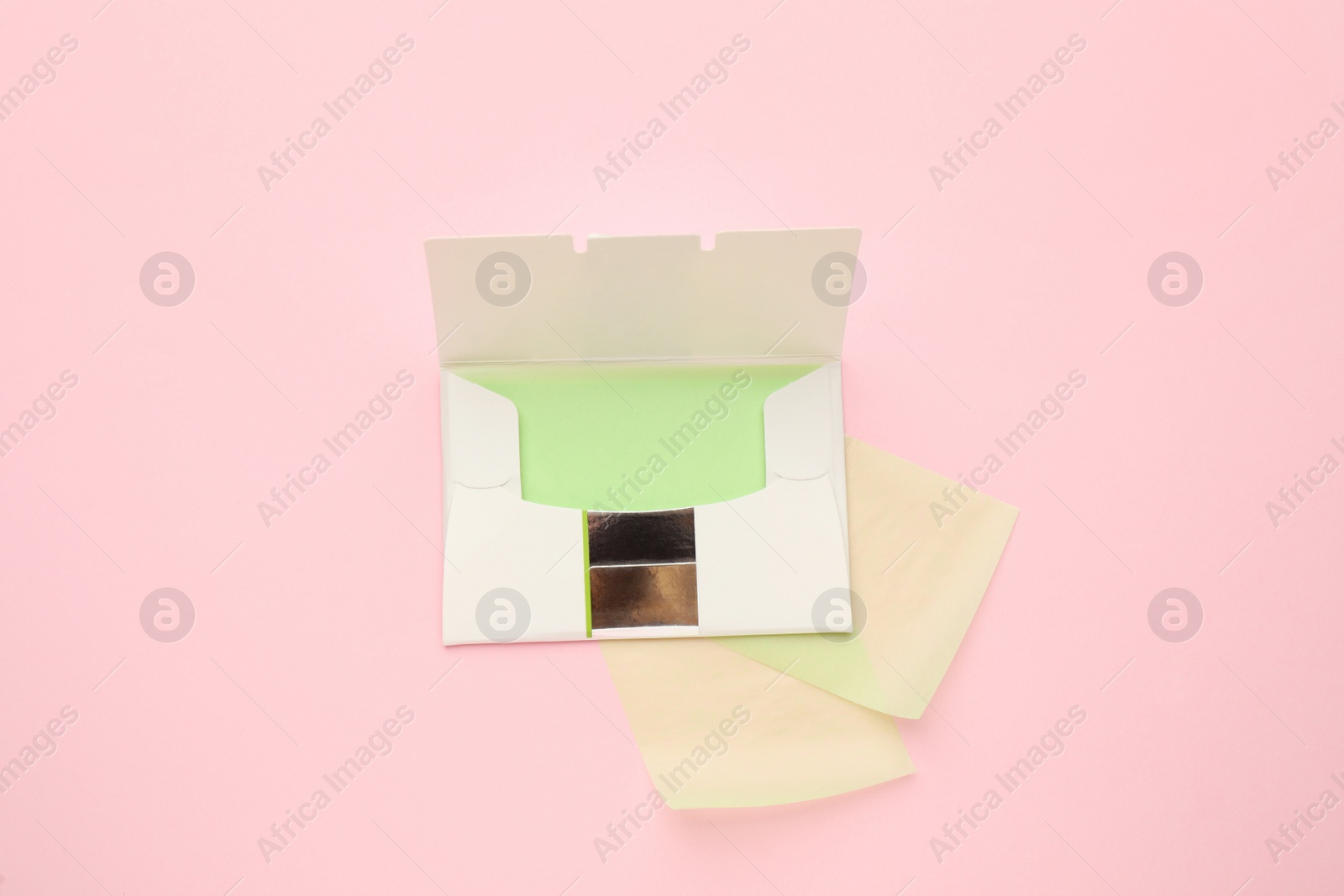 Photo of Package with facial oil blotting tissues on pink background, flat lay. Mattifying wipes