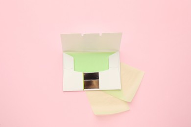 Photo of Package with facial oil blotting tissues on pink background, flat lay. Mattifying wipes