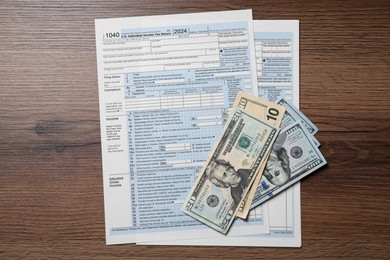 Photo of Payroll. Tax return forms and dollar banknotes on wooden table, flat lay