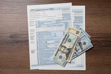 Payroll. Tax return forms and dollar banknotes on wooden table, flat lay