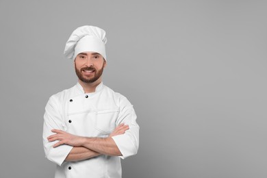 Photo of Smiling mature chef on grey background, space for text
