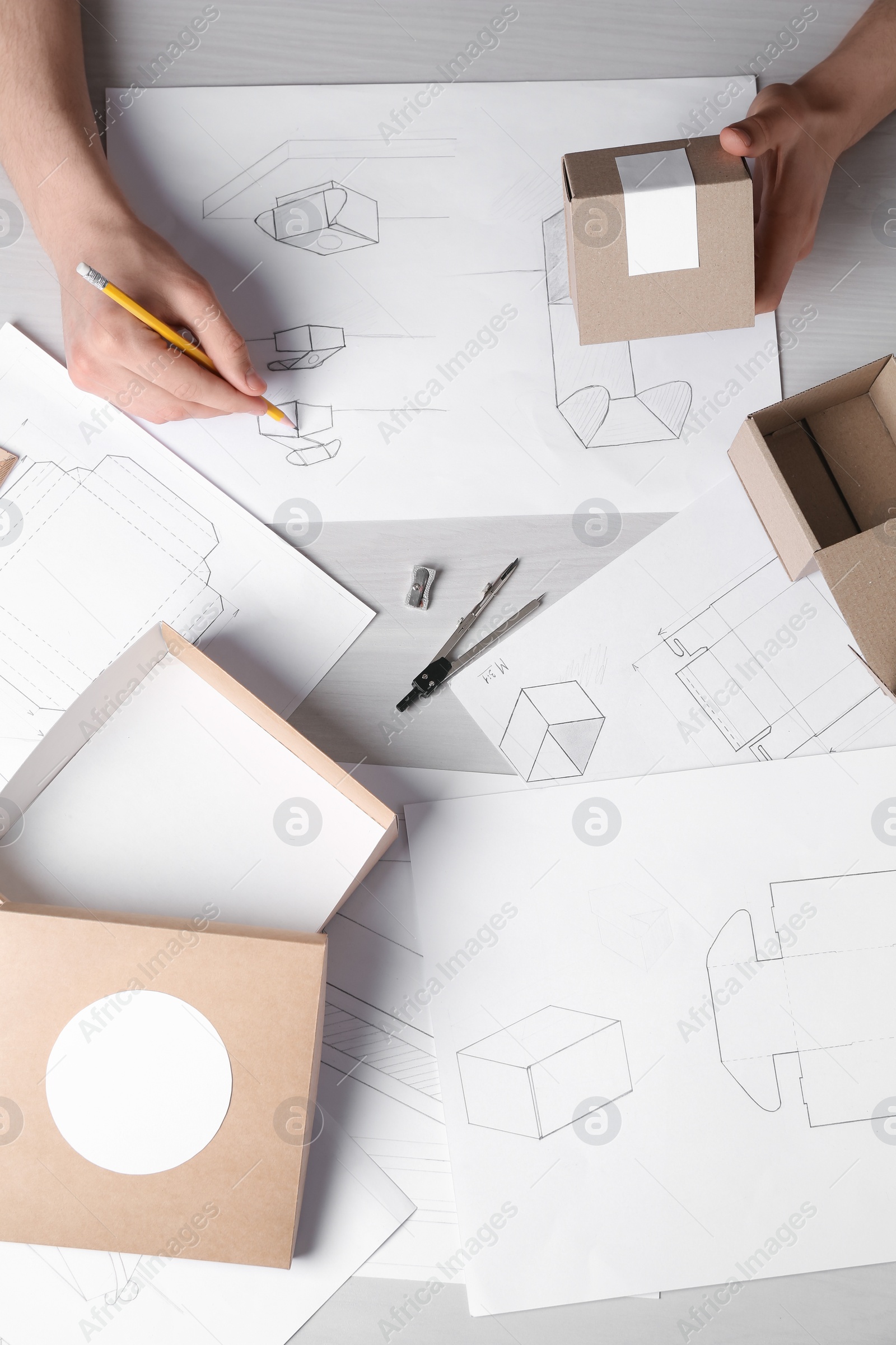 Photo of Man creating packaging design at light wooden table, top view