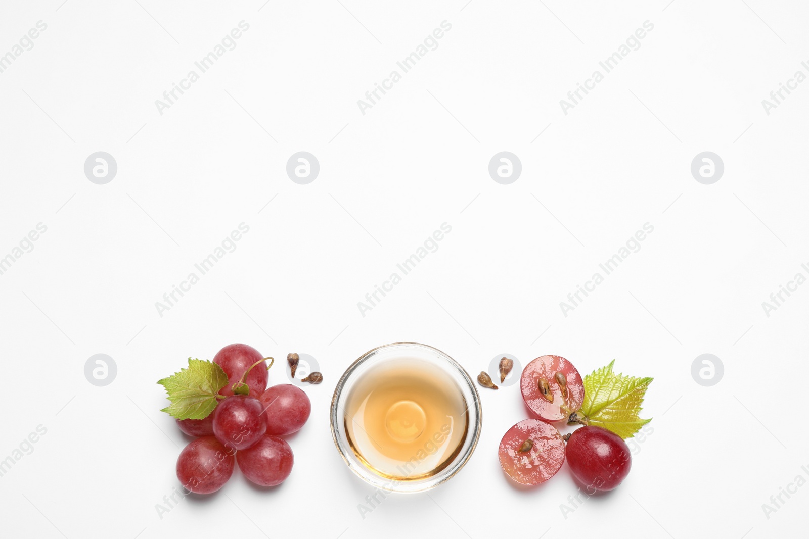 Photo of Composition with bowl of natural grape seed oil on white background, top view. Organic cosmetic