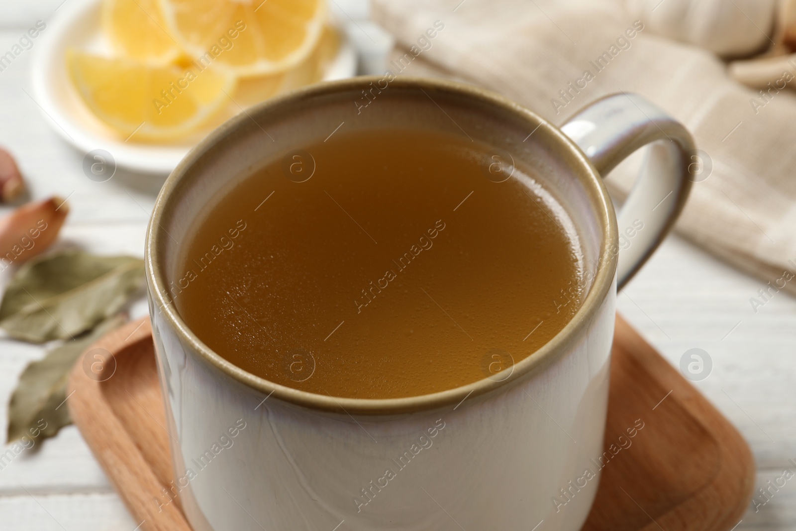 Photo of Hot delicious bouillon in cup on white table, closeup