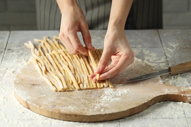 Photo of Woman with homemade pasta at light tiled table, closeup