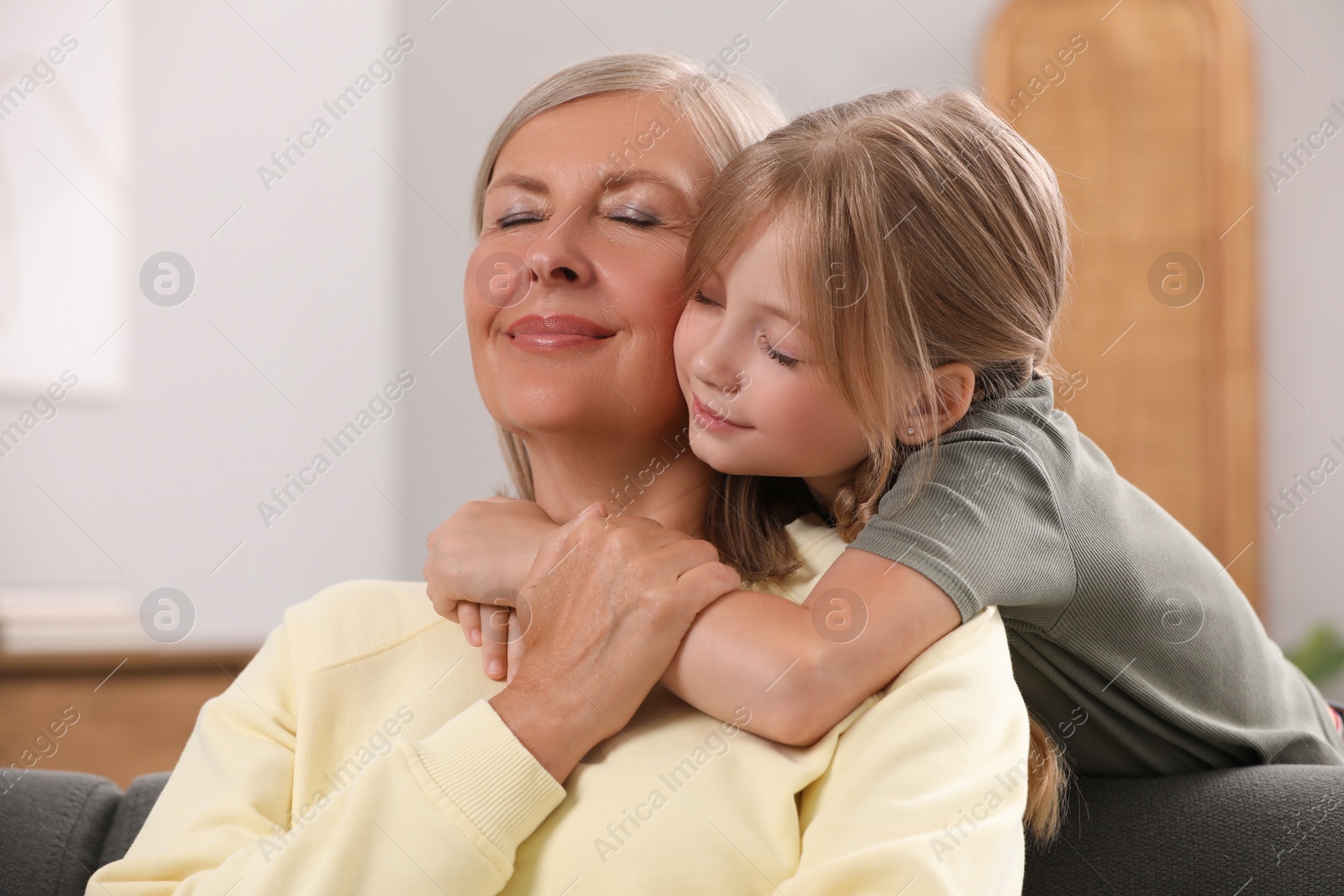 Photo of Happy grandmother hugging her granddaughter at home