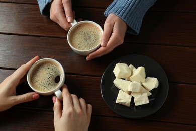 Photo of Women having coffee break at wooden table, top view