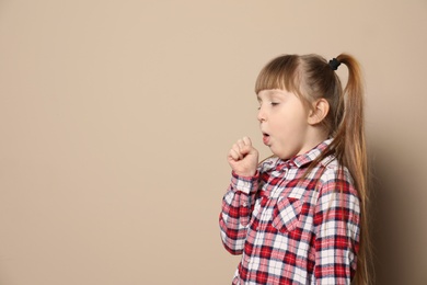 Photo of Cute little girl coughing against color background. Space for text