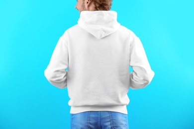 Man in hoodie sweater on color background. Space for design