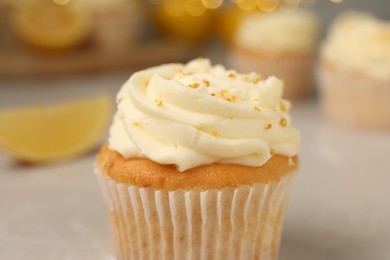 Photo of Tasty cupcake with cream and lemon zest on light table, closeup