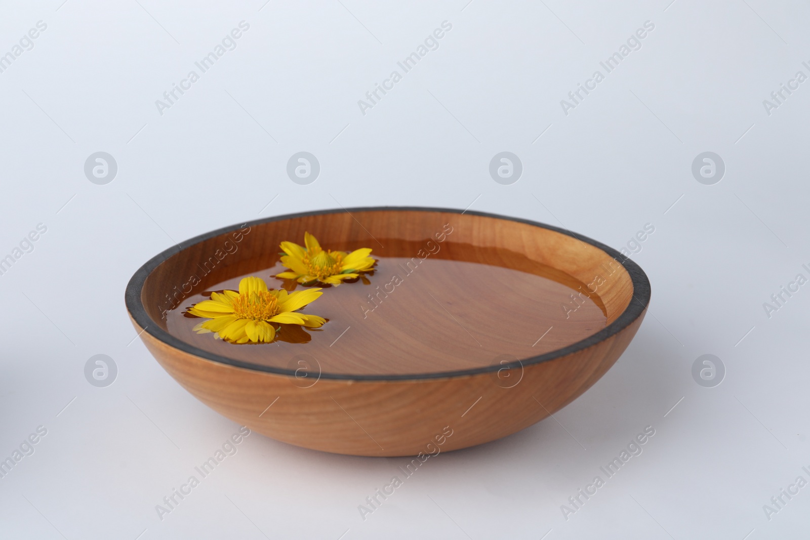 Photo of Water with flowers in wooden bowl on white background