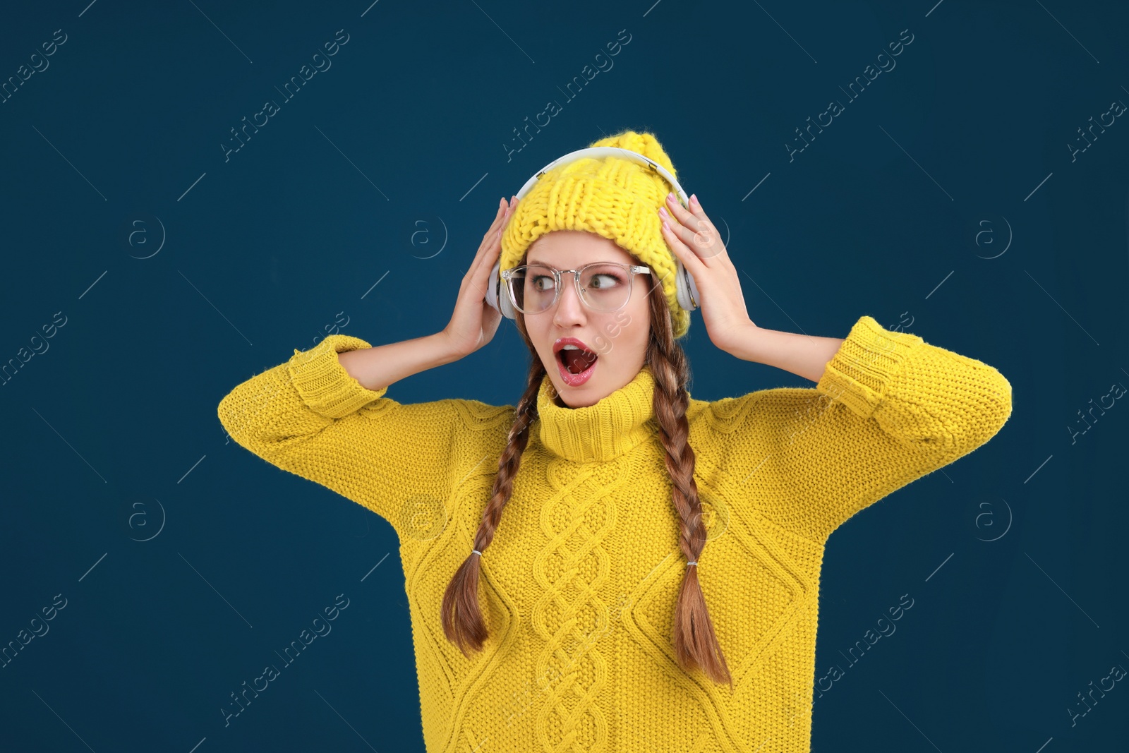 Photo of Young woman listening to music with headphones on dark blue background