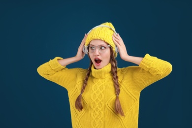 Photo of Young woman listening to music with headphones on dark blue background