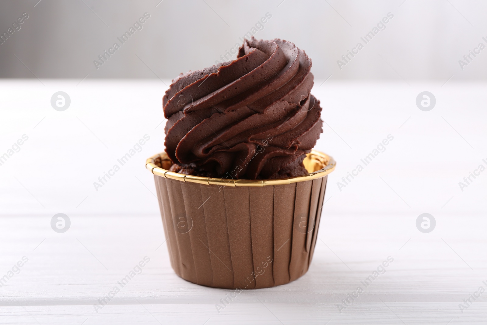 Photo of Delicious chocolate cupcake on white wooden table, closeup