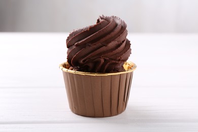 Photo of Delicious chocolate cupcake on white wooden table, closeup