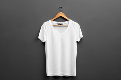 Photo of Hanger with blank t-shirt on grey background. Mockup for design