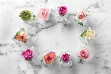 Photo of Frame made of ice cubes with flowers on marble background, flat lay. Space for text