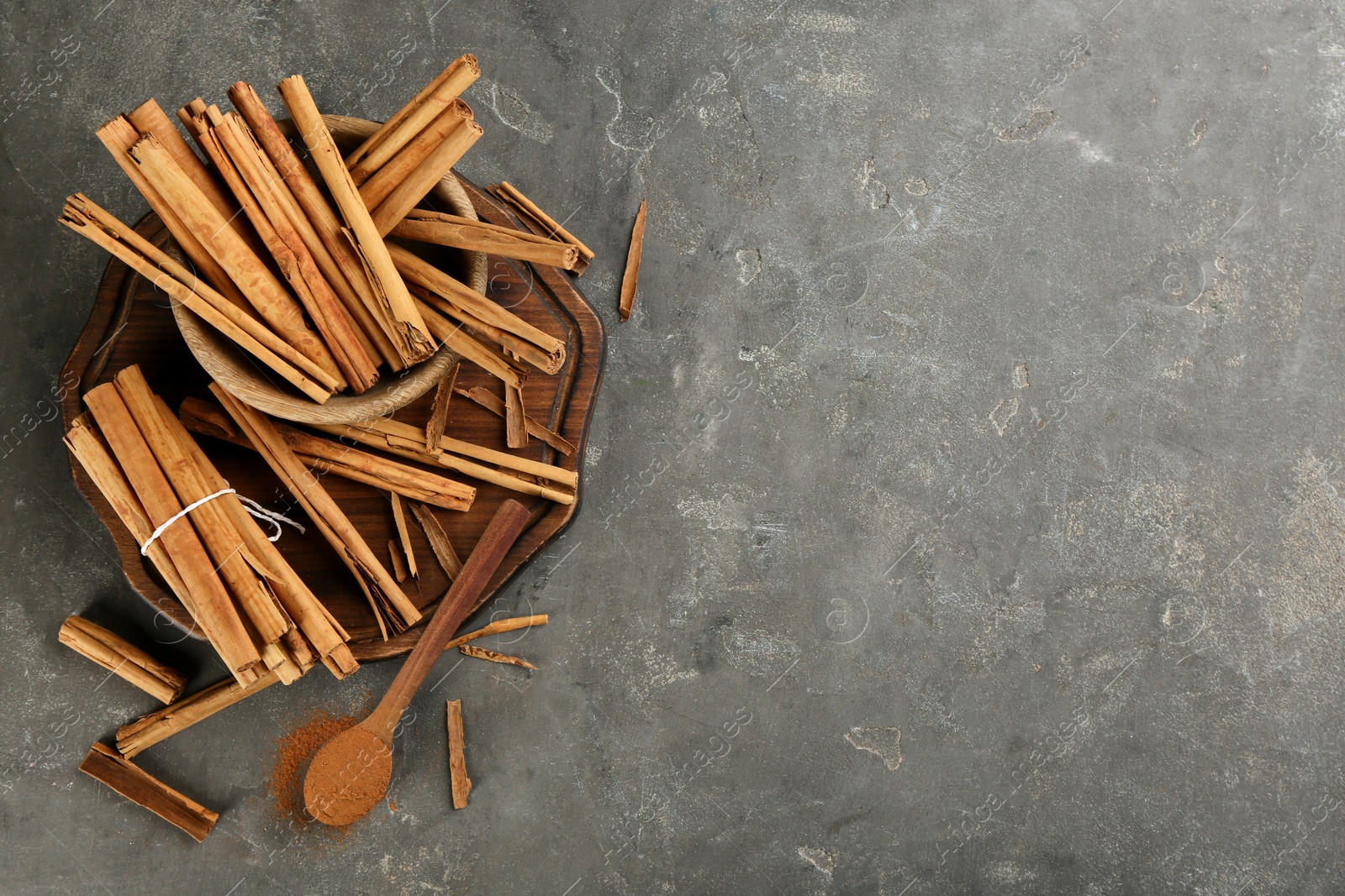 Photo of Aromatic cinnamon sticks and powder on grey table, flat lay. Space for text