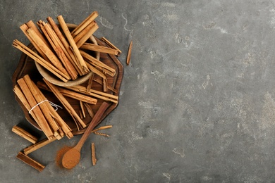 Photo of Aromatic cinnamon sticks and powder on grey table, flat lay. Space for text