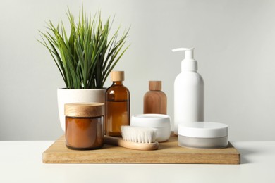 Photo of Different bath accessories and houseplant on white table against grey background