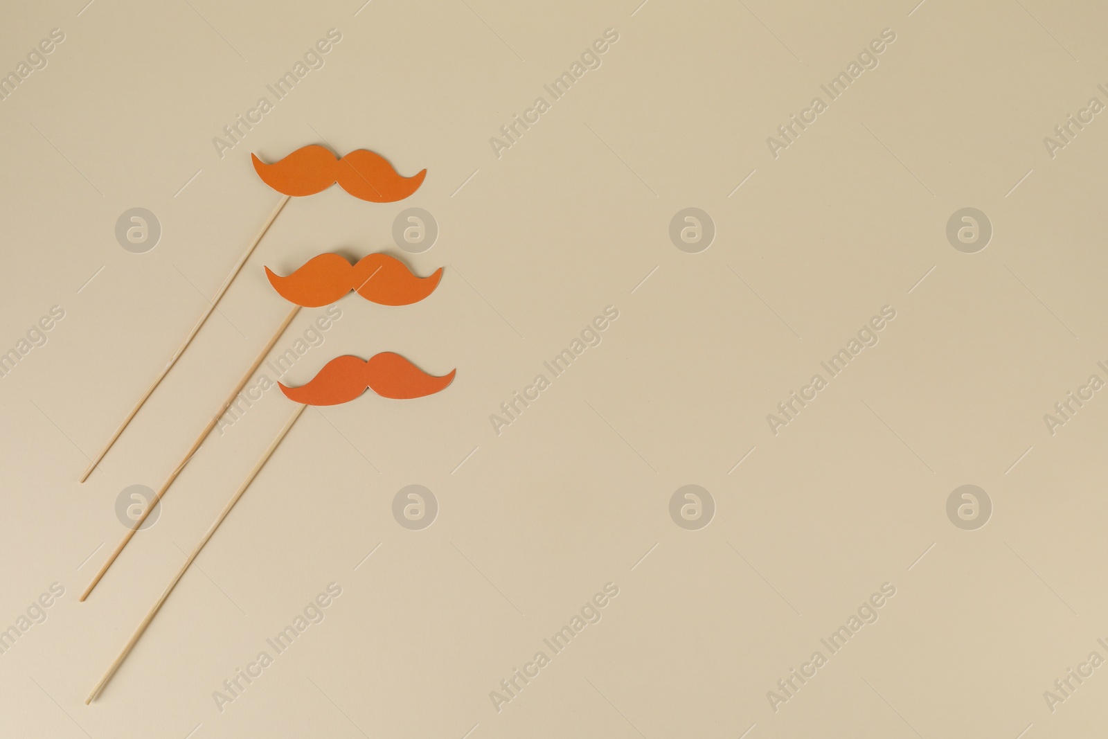 Photo of Fake paper mustaches party props on beige background, flat lay. Space for text