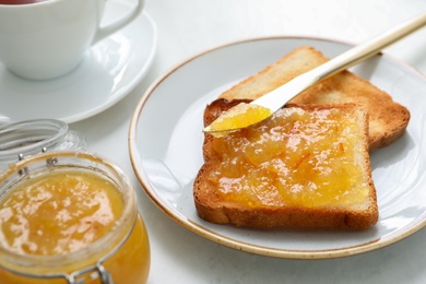 Photo of Delicious orange marmalade and toasts on white table, closeup
