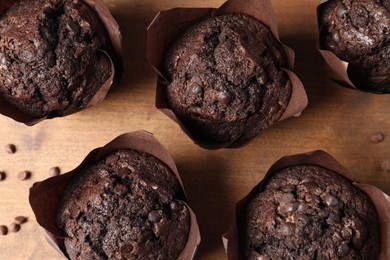 Photo of Tasty chocolate muffins on wooden board, flat lay