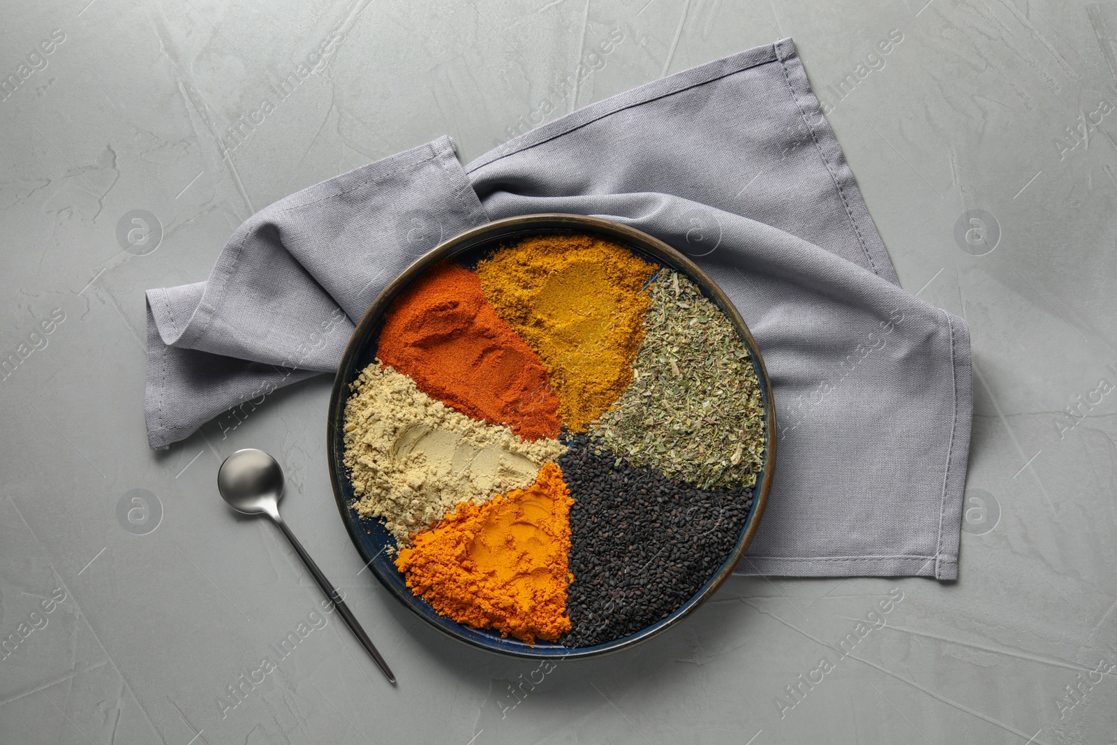 Photo of Plate with different spices on light grey table, flat lay