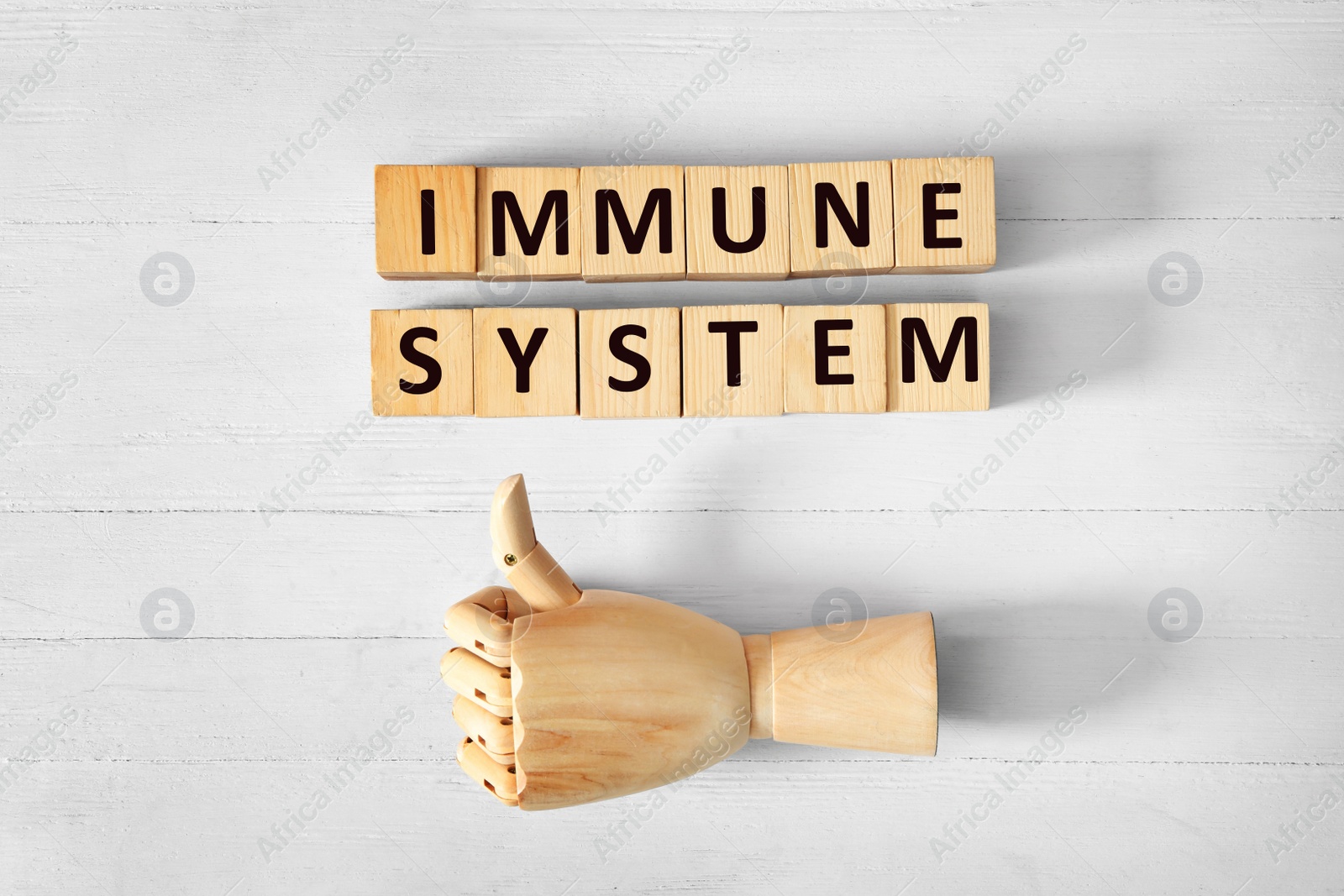 Photo of Cubes with words Immune System and mannequin hand showing thumb up gesture on white wooden table, flat lay