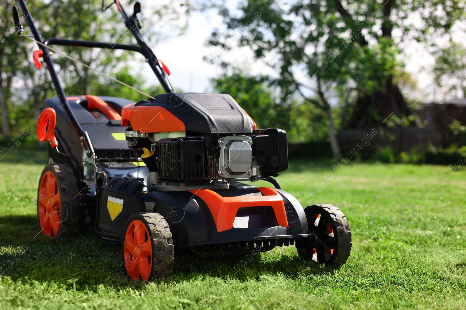 Photo of Modern lawn mower on green grass in garden