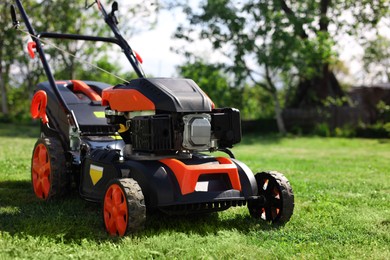 Modern lawn mower on green grass in garden